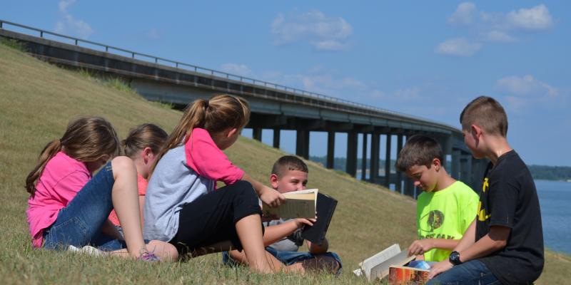 Children at the Trinity River bridge discussing a book they've read. Children at the Trinity River bridge discussing a book they've read.
